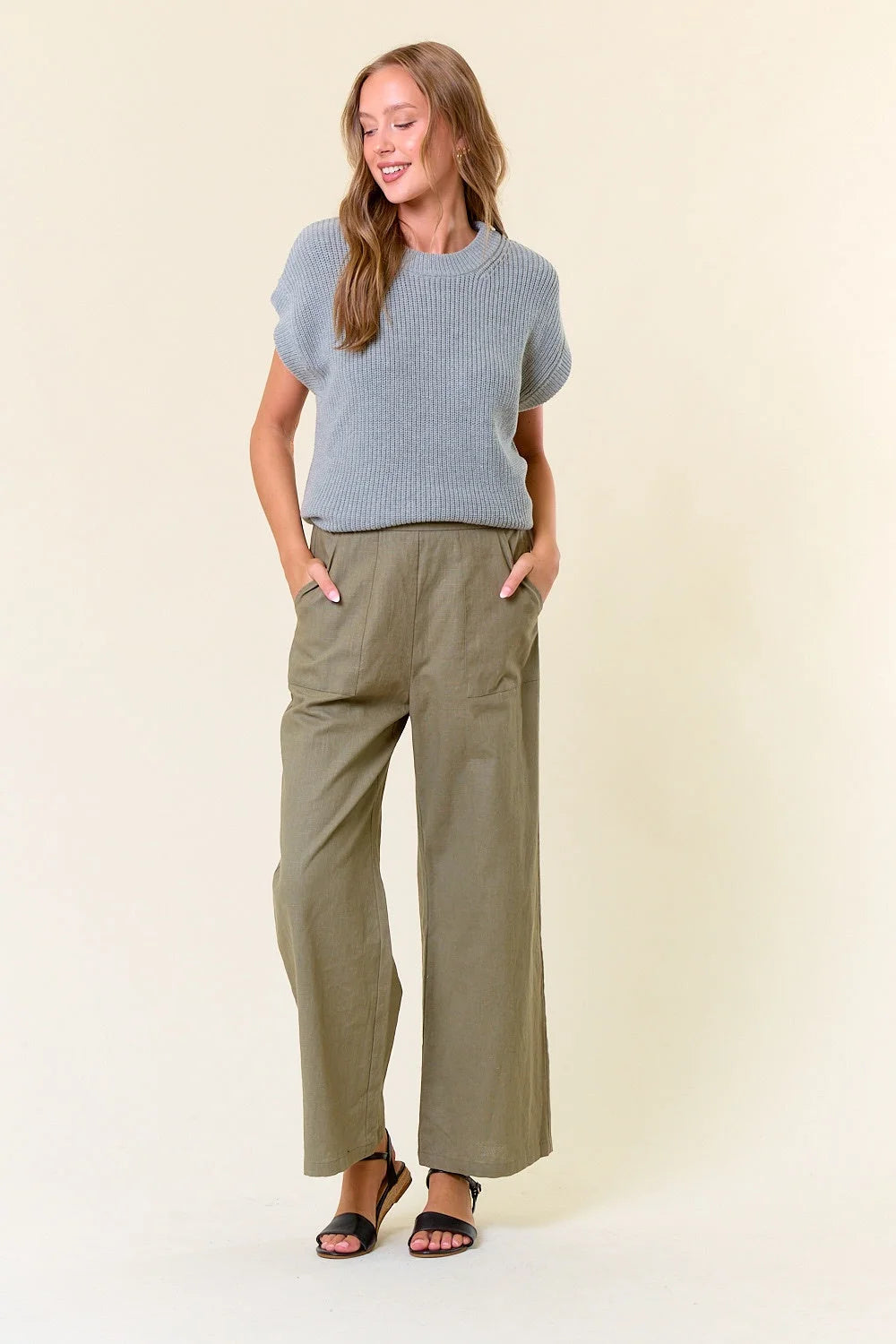 Person in blue knit top and olive green linen pants showcasing women’s boho chic clothing