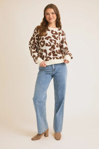 Person wearing a patterned sweater and jeans, perfect for women’s boho chic clothing