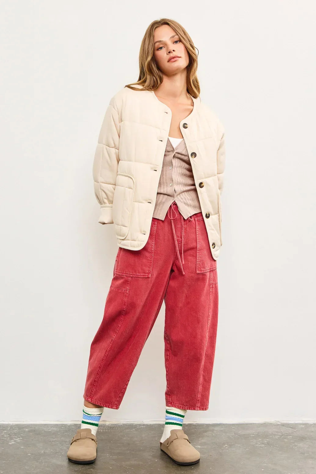 Person modeling a quilted oversized jacket with pink wide-leg pants and striped socks