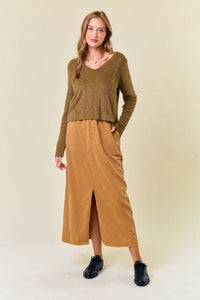 Person styled in olive green fuzzy knit top, tan midi skirt, and black shoes from Shop Daisy