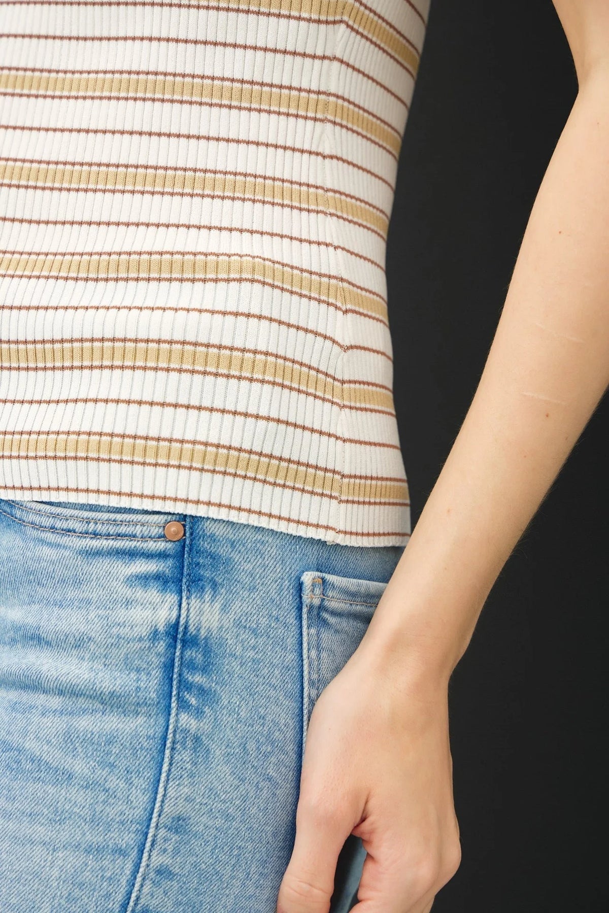 Person wearing stripe ribbed knit tank top with light-wash blue jeans