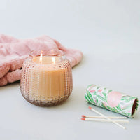 A pink blanket and a candle on a white surface featuring Sweet Grace Candle Passion Fruit & Patchouli