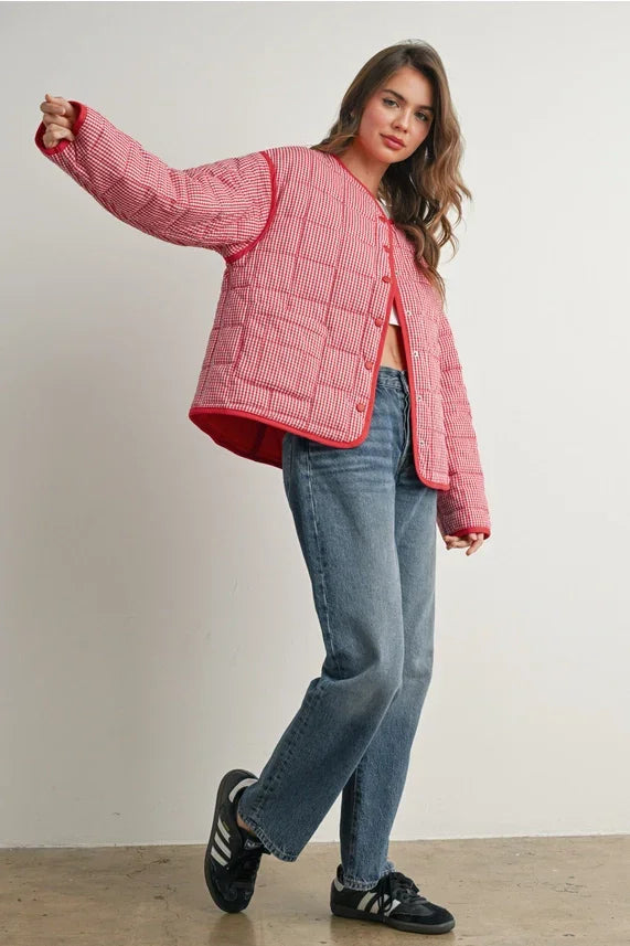 Pink buttoned quilted puffer jacket with red accents and black Adidas sneakers