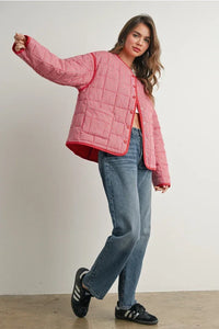 Pink buttoned quilted puffer jacket with red accents and black Adidas sneakers