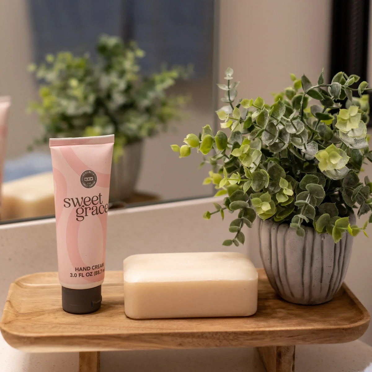 Pink Sweet Grace Hand Cream on a wooden tray with soap and a potted plant