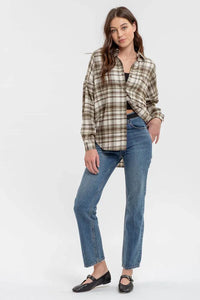 Long sleeve button down plaid shirt worn over black top with blue jeans