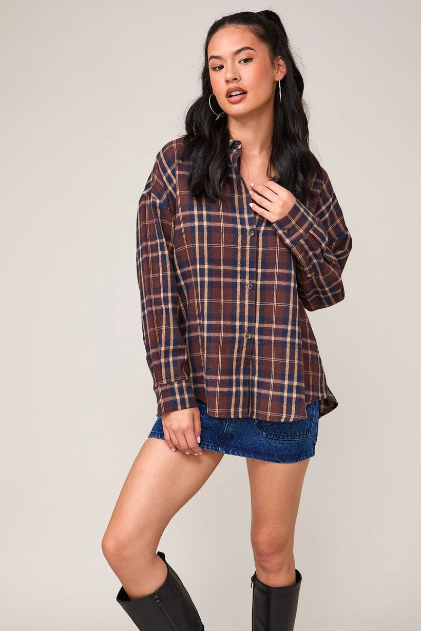 Oversized plaid shirt styled over denim shorts and paired with tall black boots