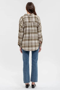 Plaid flannel long sleeve button down shirt worn over blue jeans from the back