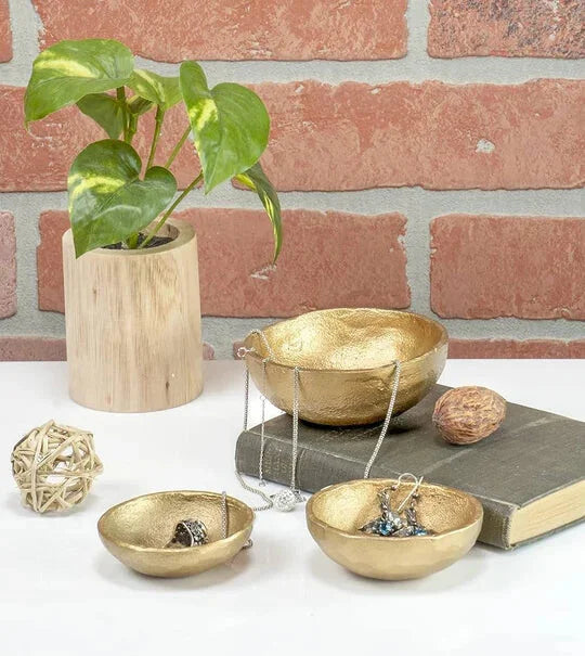 Potted green plant in wooden container with boho decorative gold bowls and accessories