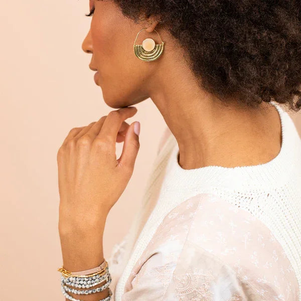 Profile view of a person with gold hoop earrings and bracelets for a boho free spirit