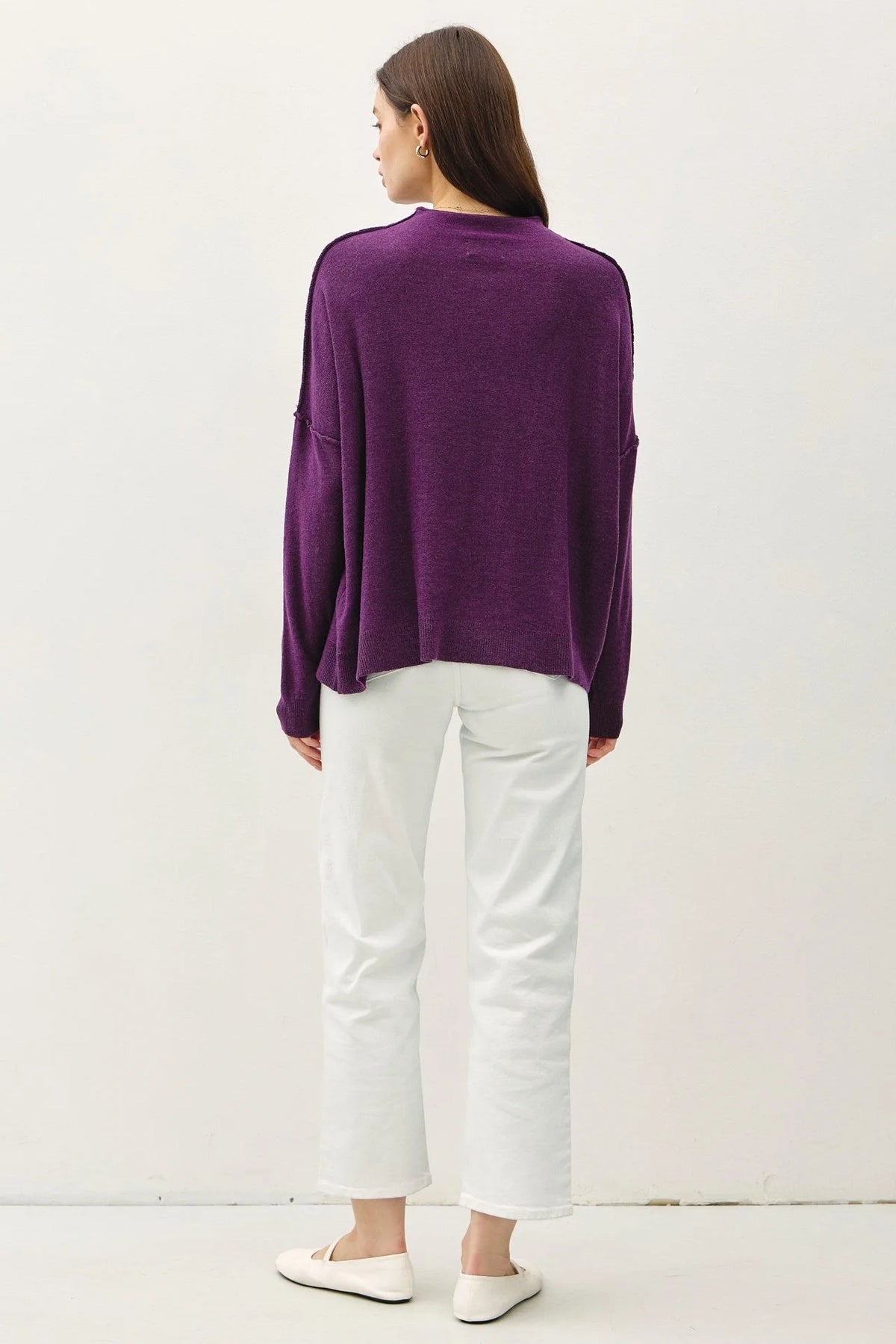 Model showcasing oversized mock neck sweater paired with white pants and shoes