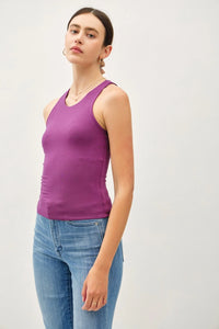 Purple sleeveless top with round neck worn by woman paired with blue jeans