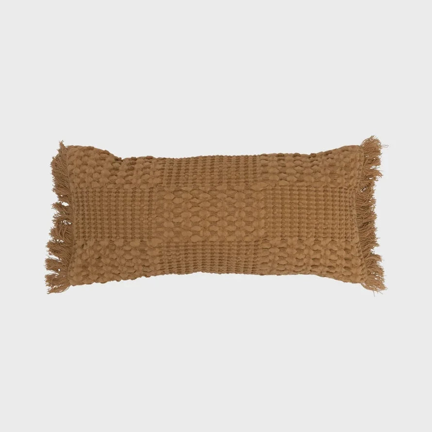 Woven cotton lumbar pillow with textured pattern and fringe edges in warm brown color