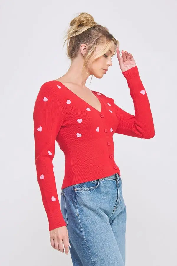 Red cardigan with textured hearts styled with blue jeans from Shop Daisy’s women’s boho chic clothing