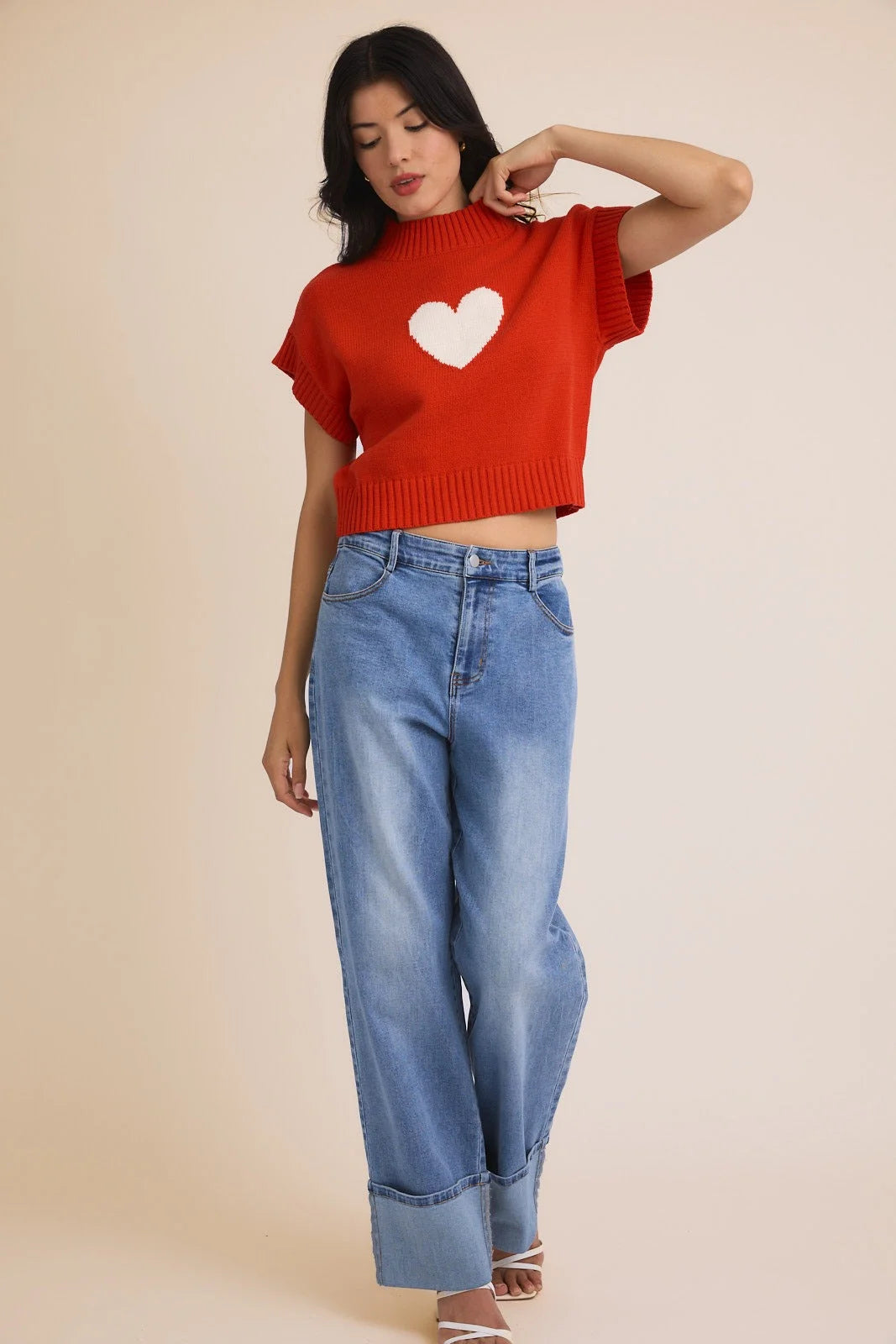 Red mock neck wide shoulder heart sweater paired with cuffed wide-leg jeans