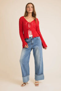 Red open knit cardigan with tie front and bell sleeves styled with wide-leg cuffed jeans