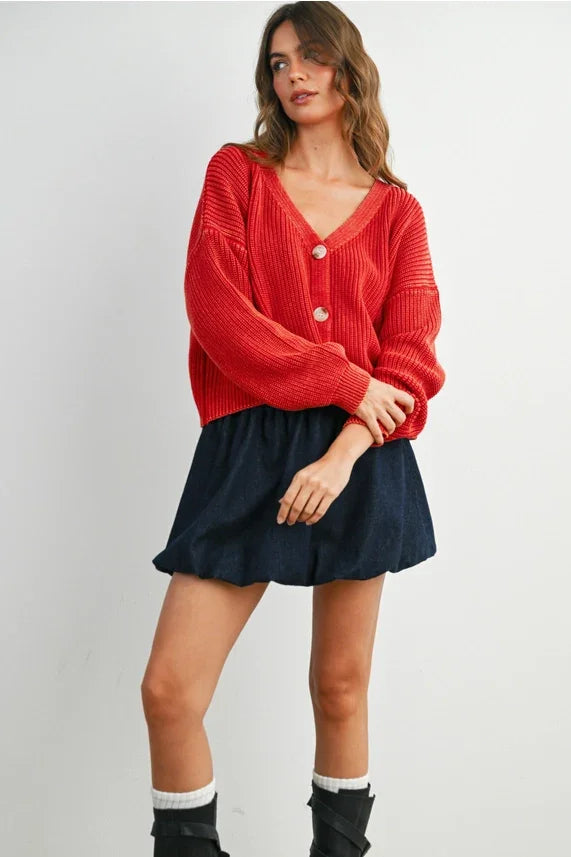 Red knit V neck buttoned ribbed long sleeve cardigan over navy blue bubble skirt
