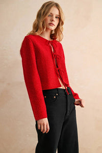 Red lace-up long sleeve cardigan with black pants and gold buttons