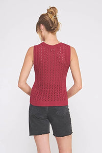 Red sleeveless crochet sweater vest with open-knit design and dark gray denim shorts