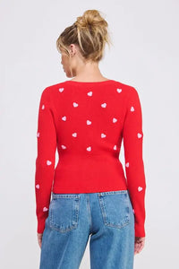 Red sweater with textured hearts styled with blue jeans from Shop Daisy’s women’s boho chic clothing