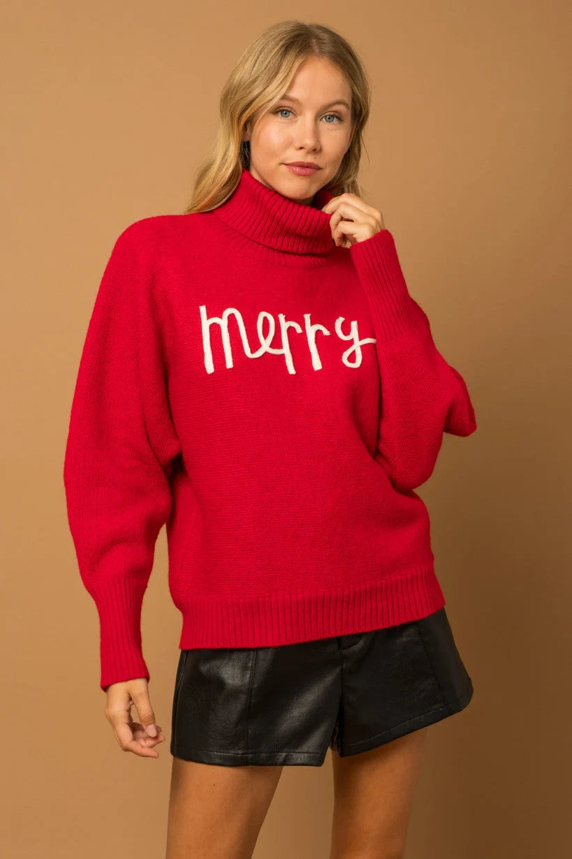 Red turtleneck sweater with merry text, perfect for women’s boho chic clothing at Shop Daisy