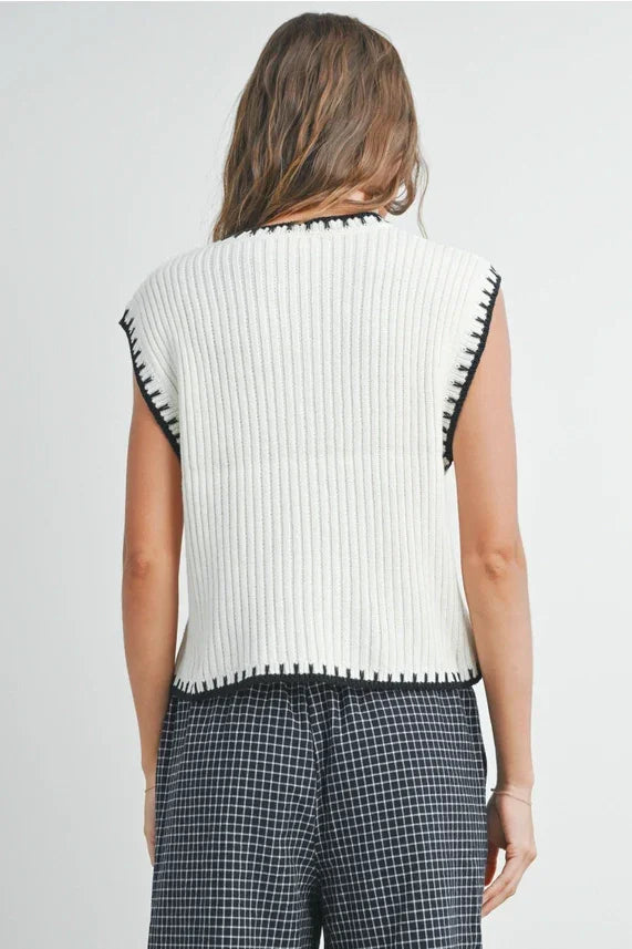 Solid cap sleeve sweater vest with ribbed knit, black contrast stitching, and checkered pants