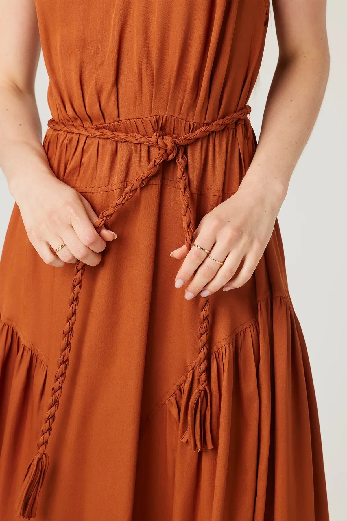 Rust-colored AURA MIDI DRESS featuring boho tasseled details and a braided belt