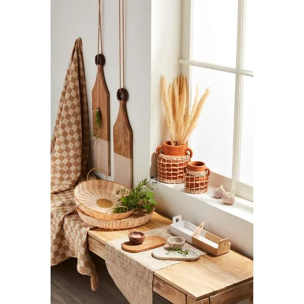 Round woven and brass tray in a rustic kitchen decor with natural wood and woven textiles