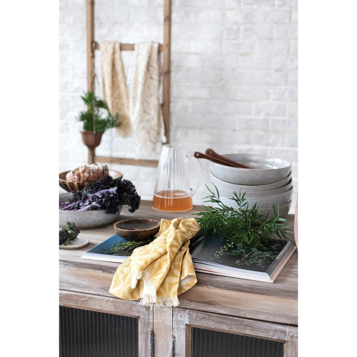 Rustic wooden table showcasing a cotton printed kitchen towel with various items