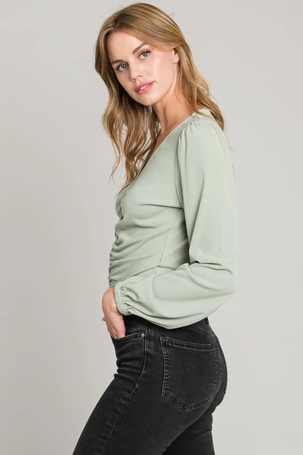 Sage green long-sleeved wrap top from Shop Daisy in center ruched style with dark jeans