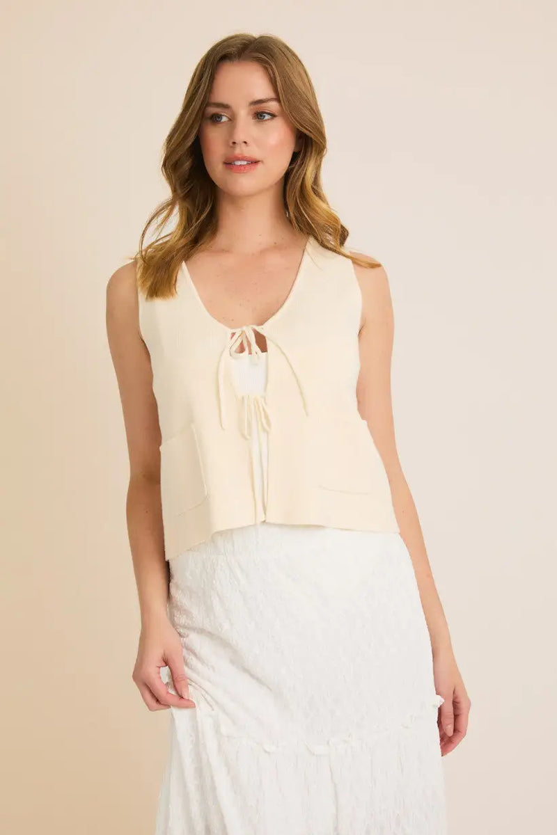 Sleeveless cream-colored tie-front top featured in a stylish tie sweater vest