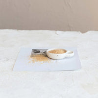 Small bowl of brown sugar in a stoneware dish with handle on a white table