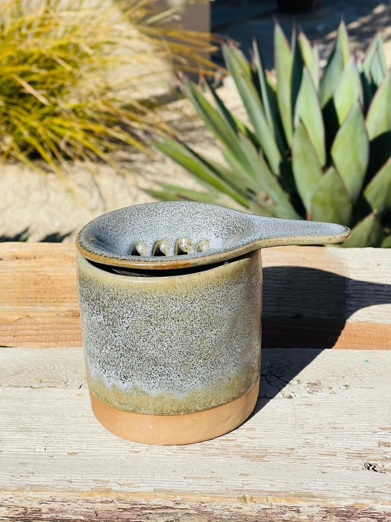 Small pot with a lid on a wooden table, complementing the TEA MUG, CUP & SAUCER set