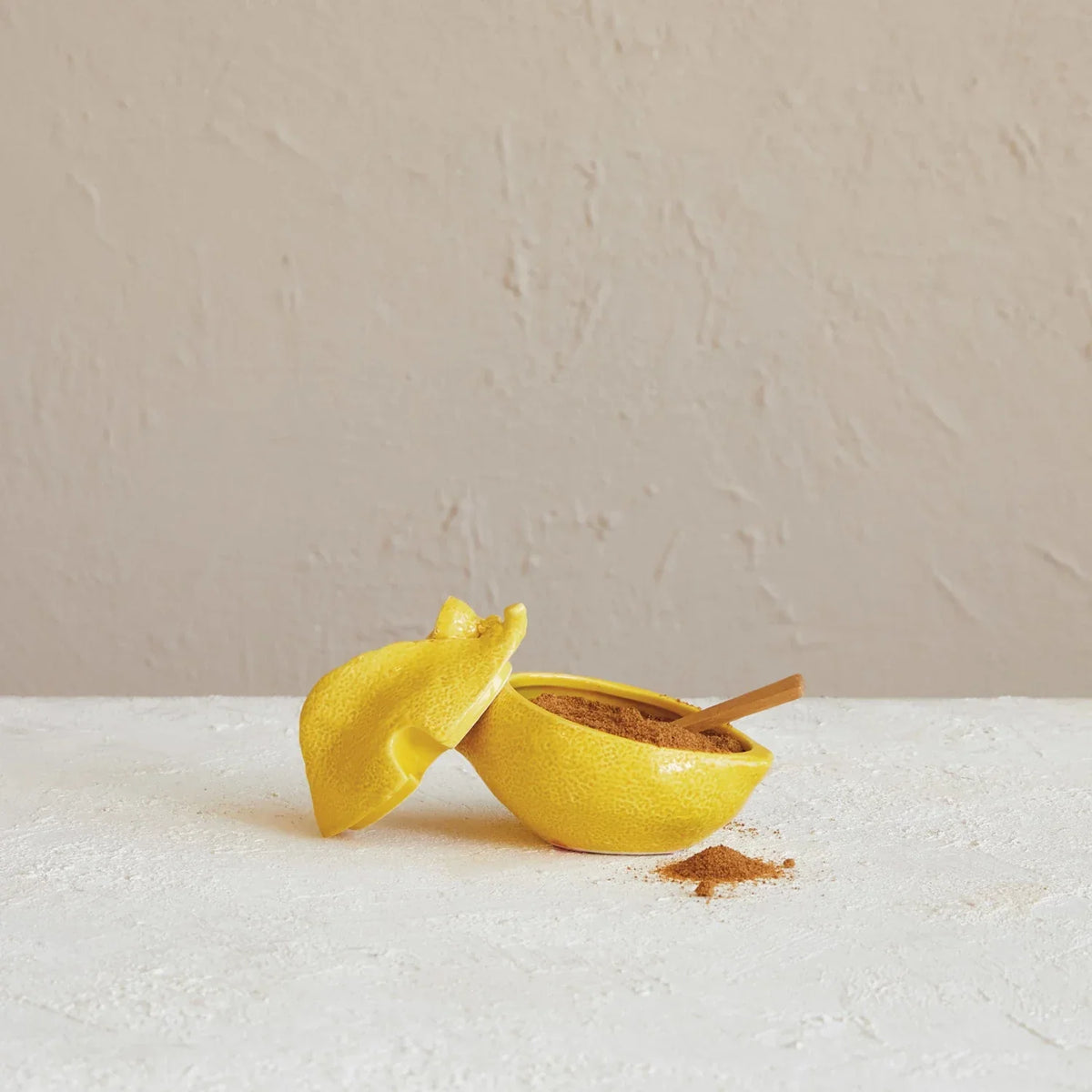 Small yellow lemon on white table beside Stoneware Lemon Shaped Sugar Pot Wood Spoon