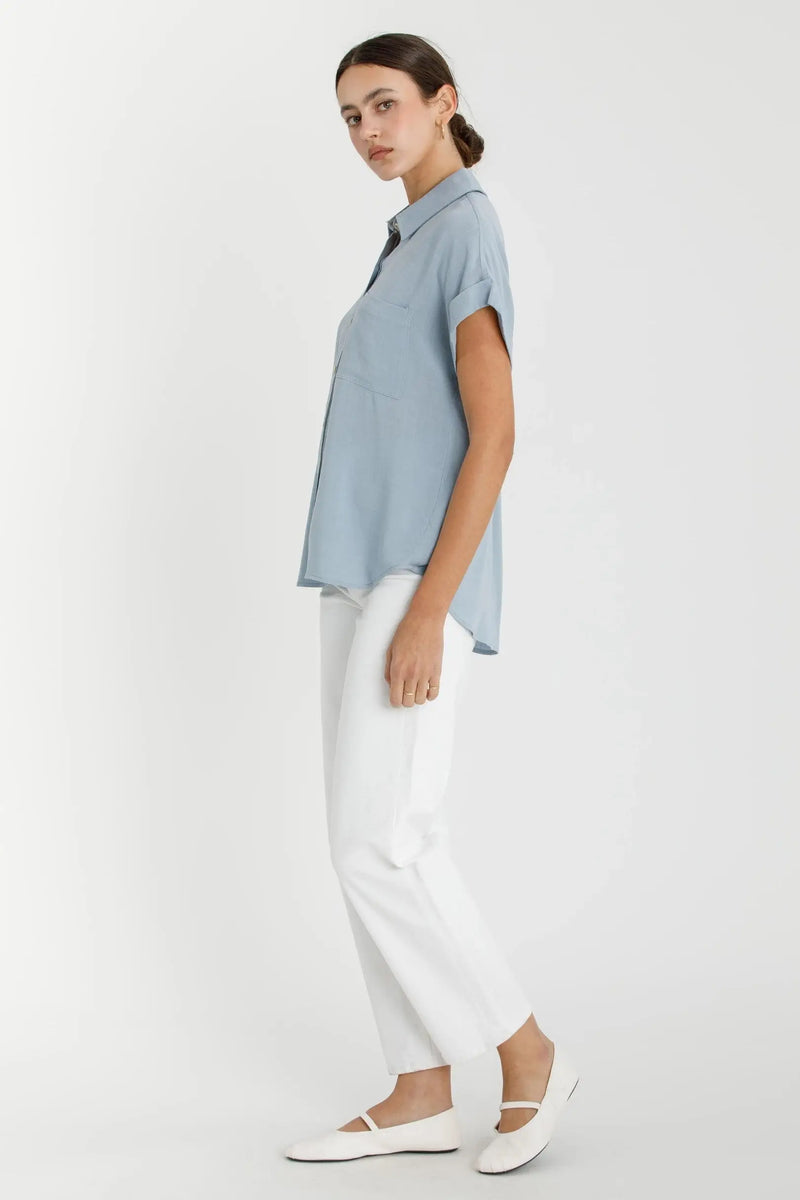 Woman wearing a blue shirt from SOLID SHORT SLEEVE BUTTON DOWN SHIRT, ideal for women’s boho chic clothing at Shop Daisy