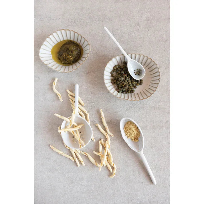 Spoons and bowls of food on a table featuring a Stoneware Strainer Spoon