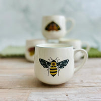 White stoneware mug with vibrant colored rim and black and yellow bumblebee design