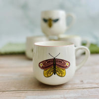 White stoneware mug with vibrant colored rim and butterfly design