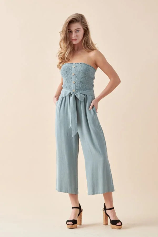 Soft linen smocked tube jumpsuit in light blue with wide cropped legs and front tie waist