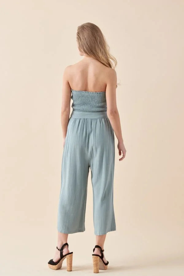 Woman wearing Soft Linen Smocked Tube Jumpsuit with wide-leg cropped pants, back view