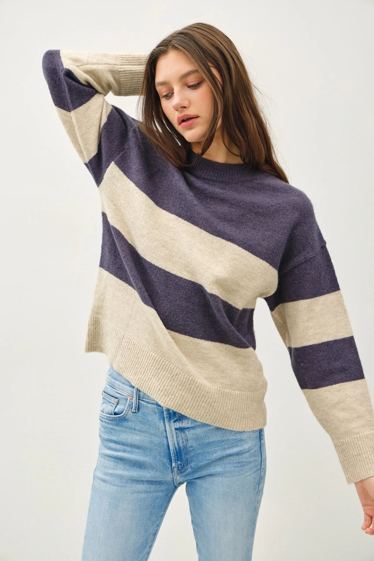 Striped pullover oversized sweater in purple and cream paired with light blue jeans