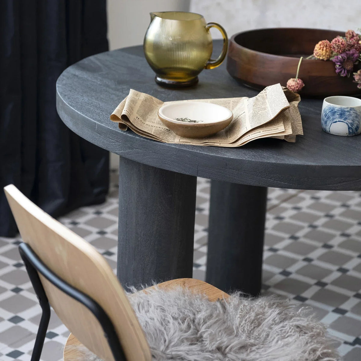 A table featuring a bowl of flowers and a book beside a Quart Fluted Glass Pitcher