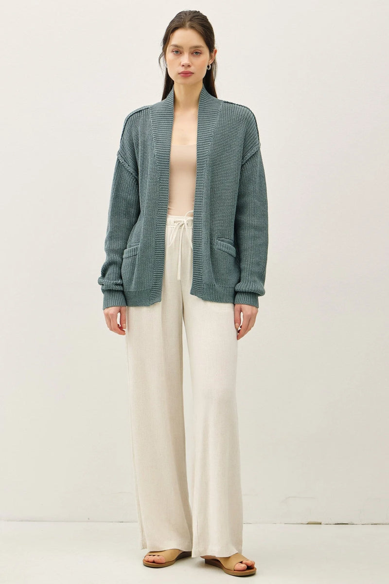 Teal textured chunky knit drop shoulder cardigan styled with white pants and sandals