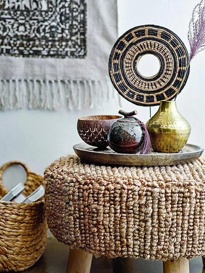 Textured round ottoman with woven jute beside a Hammered Metal Finish Vase