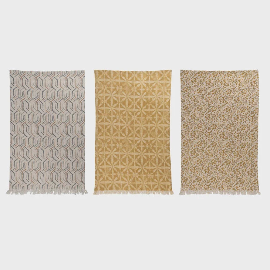 Three decorative area rugs with geometric patterns in neutral tones near cotton printed kitchen towel