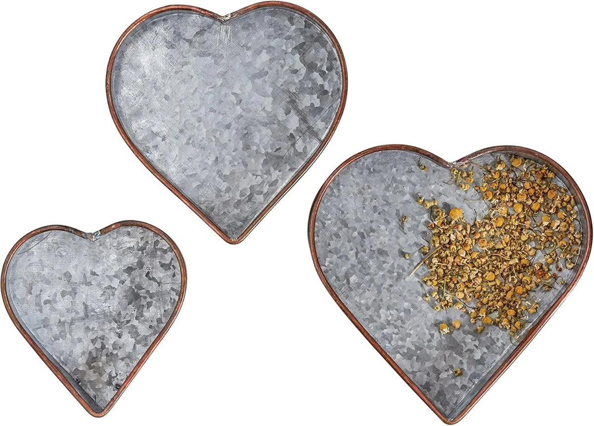 Three heart shaped galvanized metal trays with copper edges and gold accents