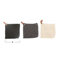 Three crocheted pot holders in black, gray, and cream with leather hanging loops