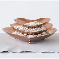 Three-tiered copper tray filled with white stones, featuring embossed metal details