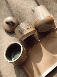 Tray displaying stackable stoneware salt and pepper shaker set with cups