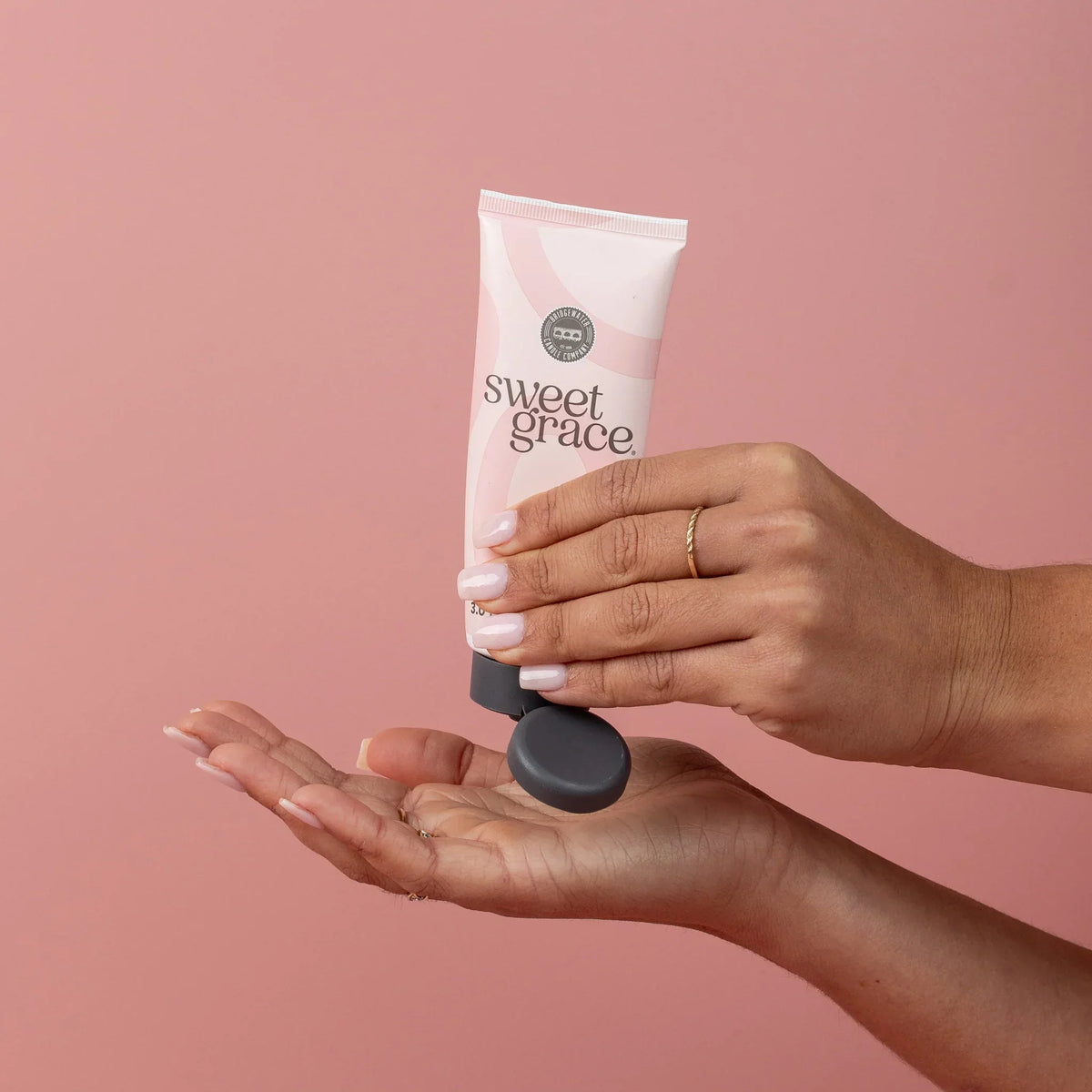 Tube of Sweet Grace Hand Cream being squeezed into hand for skincare routine